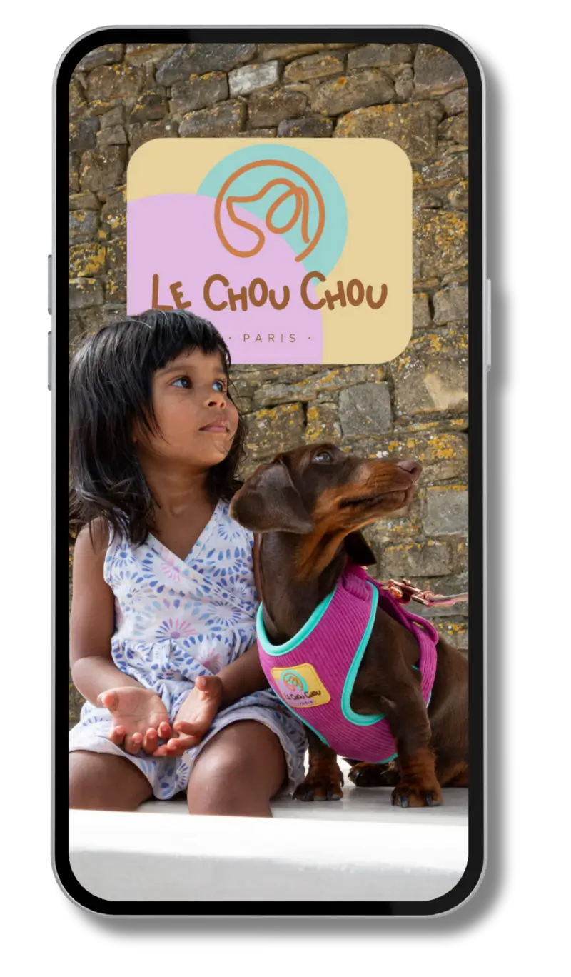 Little girl sitting beside a Dachshund wearing a pink Le ChouChou Paris dog harness, sharing a calm outdoor moment.